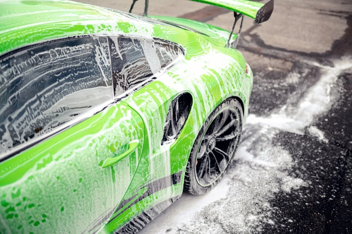 Green sports car covered in wash foam