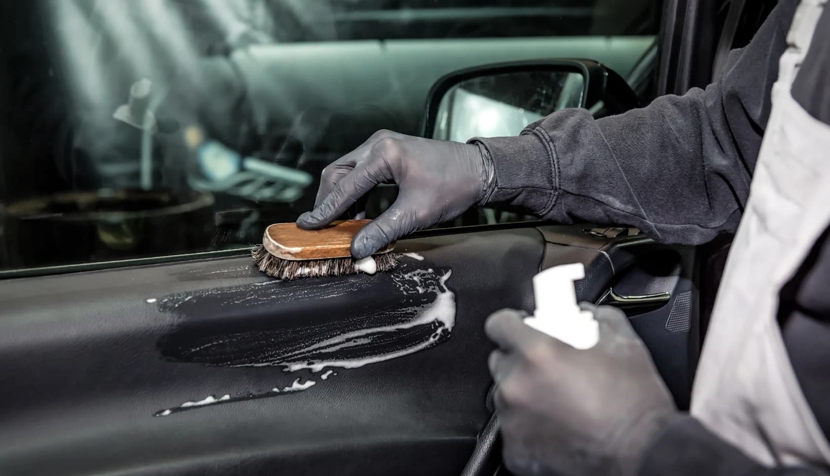 Detailer brushing and cleaning an interior door panel