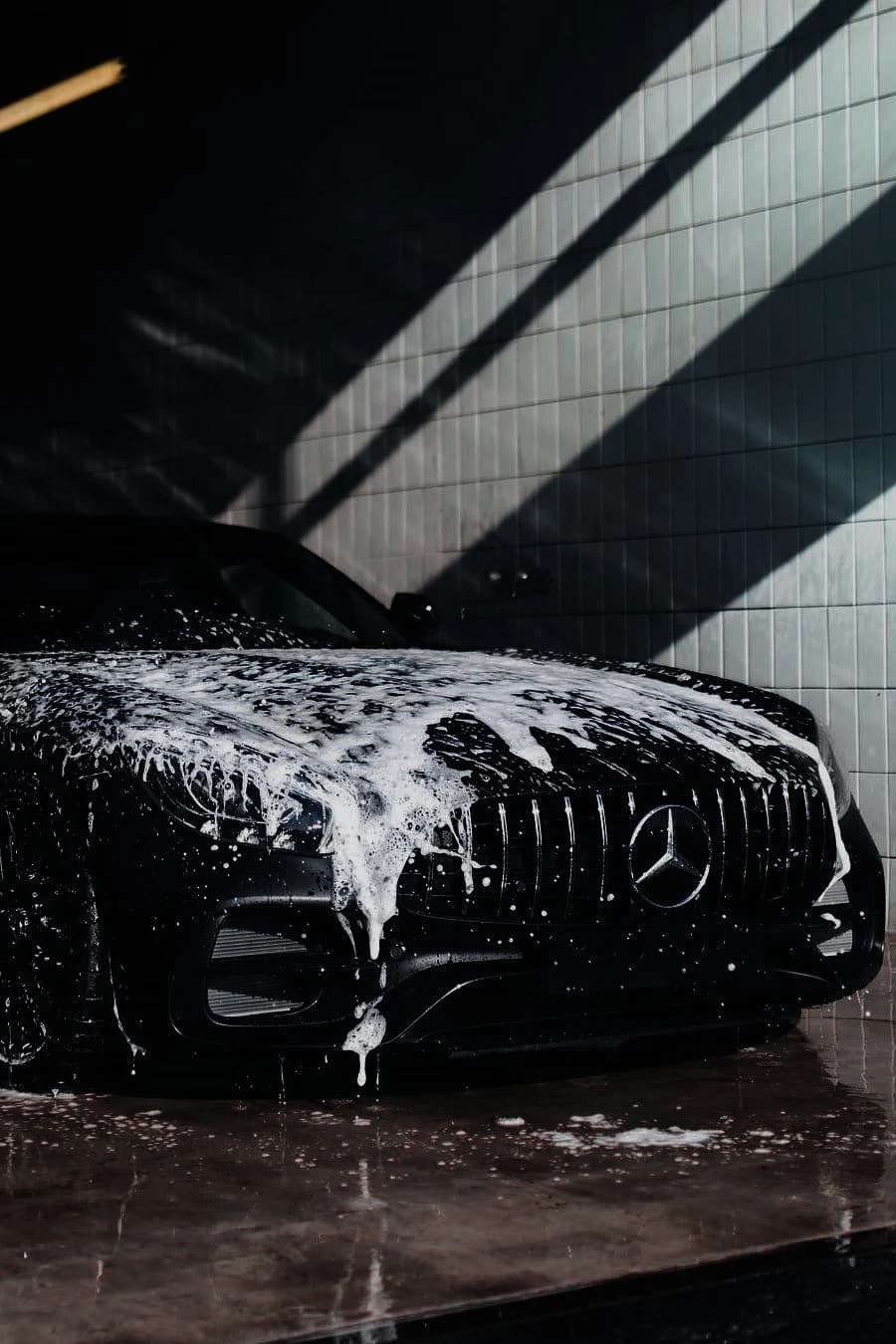 Black Mercedes covered in foam during coating preparation