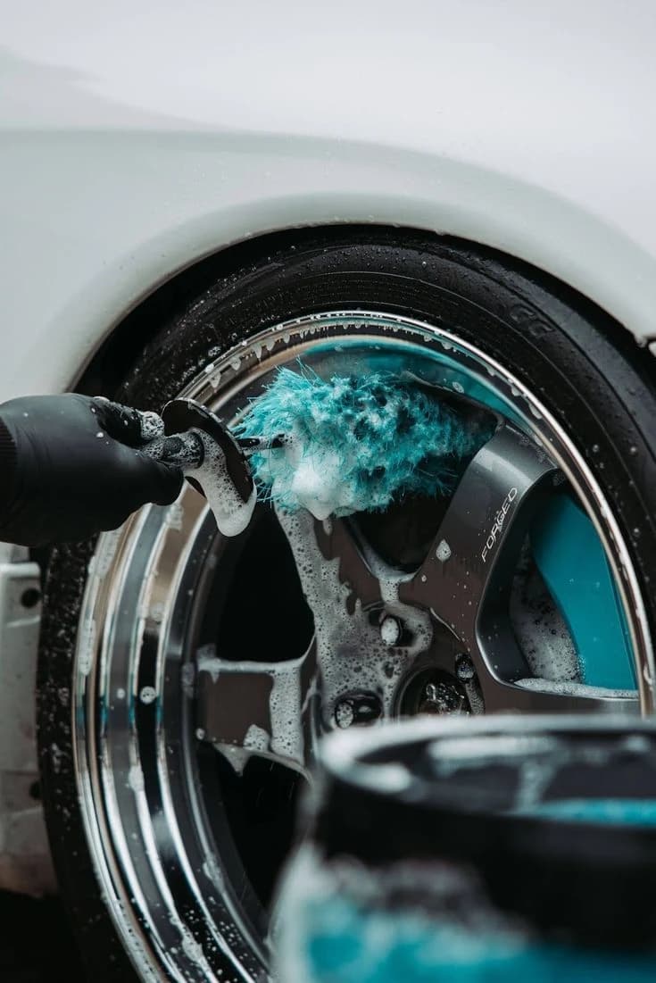 Detailer cleaning an alloy wheel with a soft brush